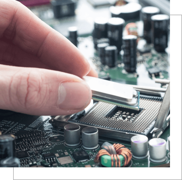 A person holding a computer chip on top of a circuit board.